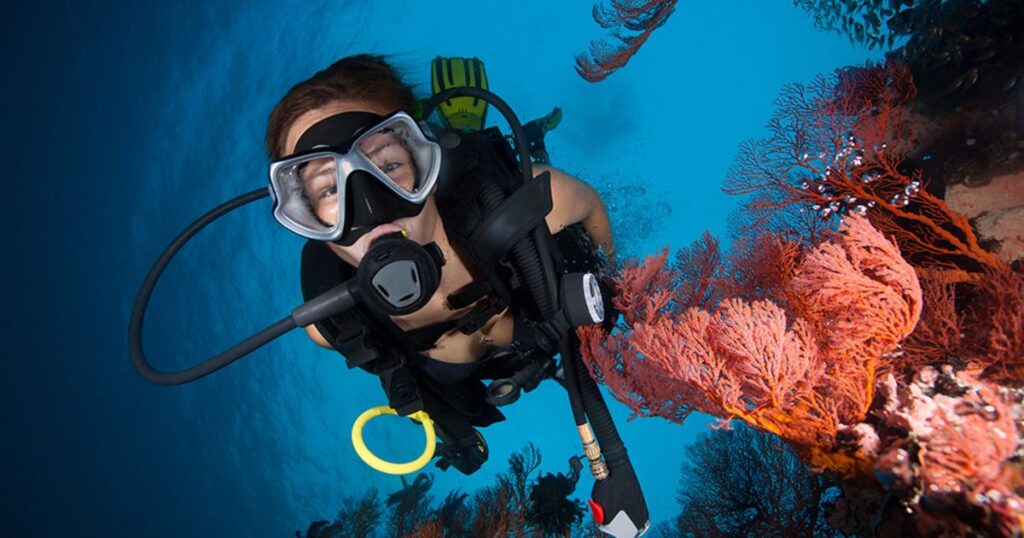 A woman swims up to the camera while scuba diving in Mexico.