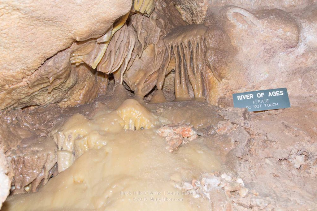 A sign says "River of Ages, Please Do Not Touch", placed in the Black Hills Caverns by some unique formations.