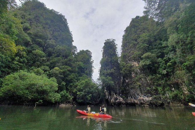 An image shows two people kayaking in the river on a tour of the Mangrove Caves in Thailand.